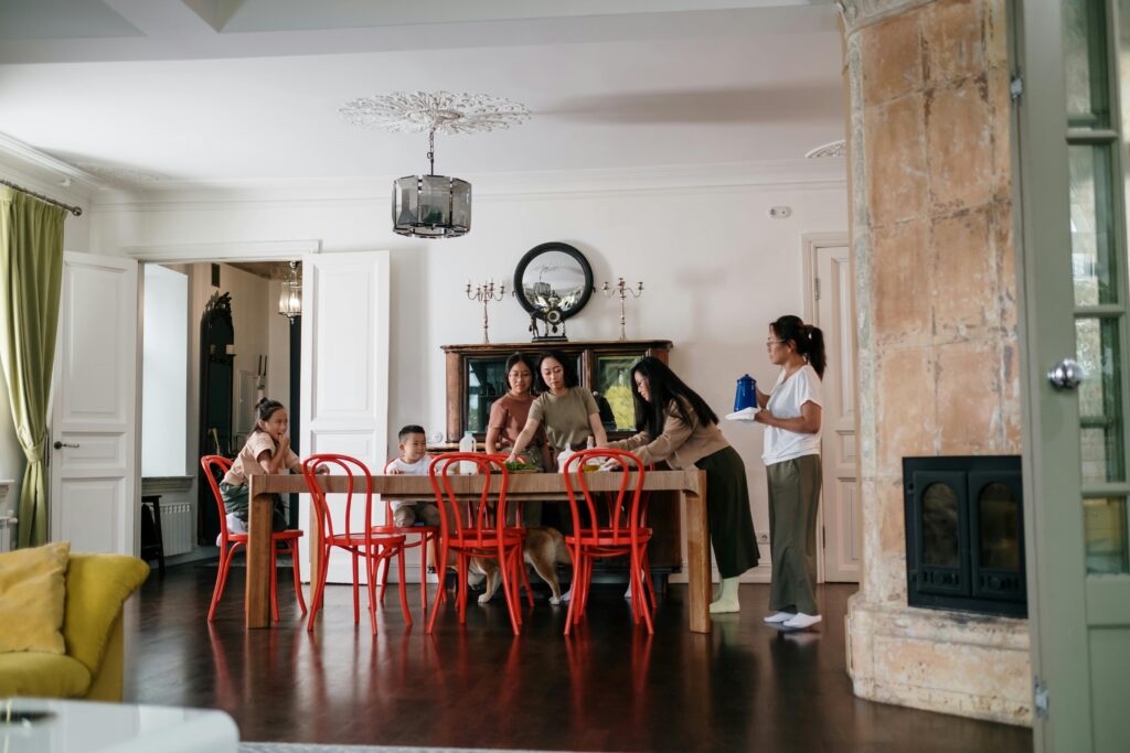 A diverse family enjoying togetherness in a modern, cozy dining room setting with red chairs.